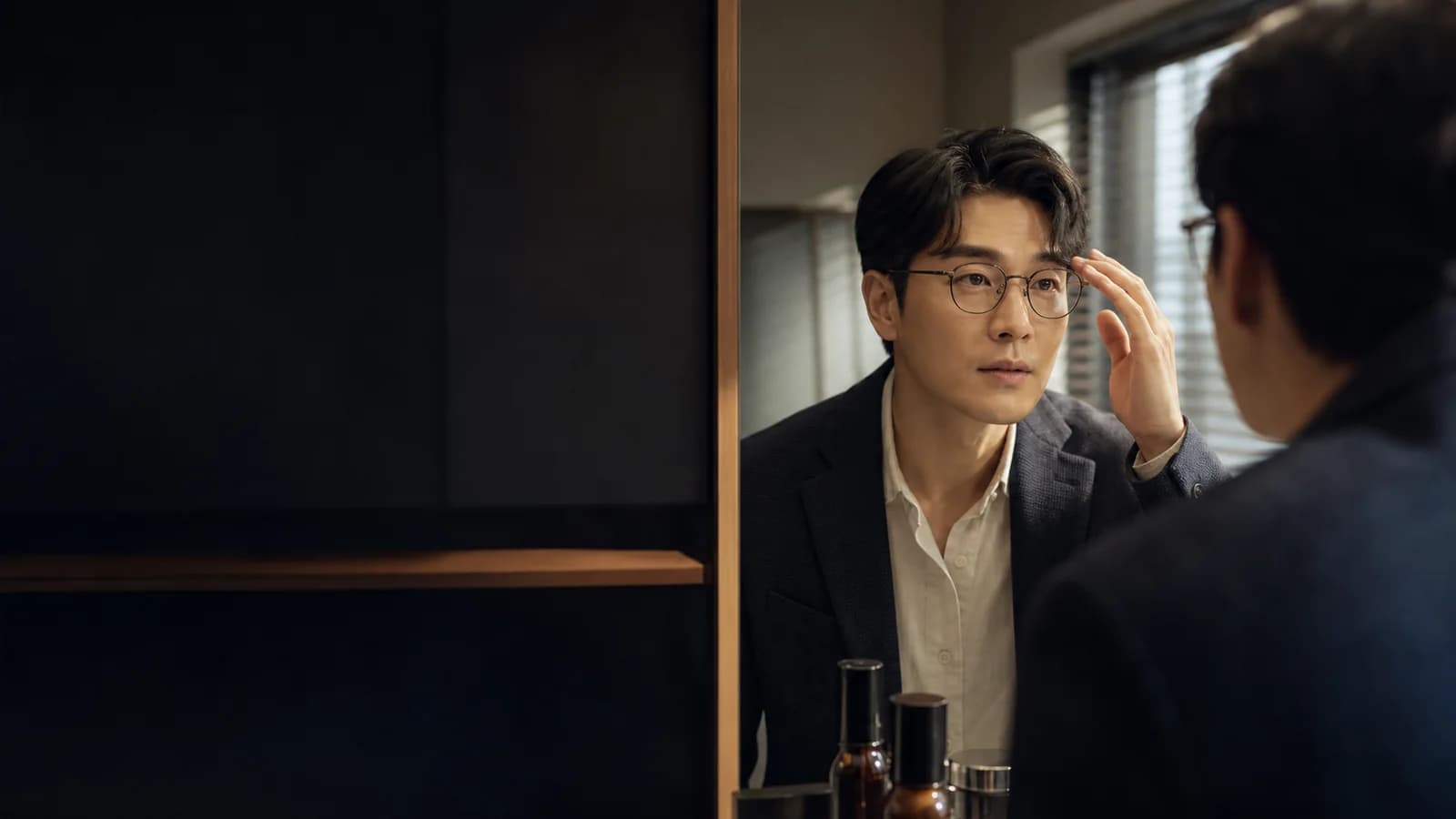 출근 복장과 안경을 착용하고 거울에서 눈썹 인상을 확인하는 성인 한국인 남성