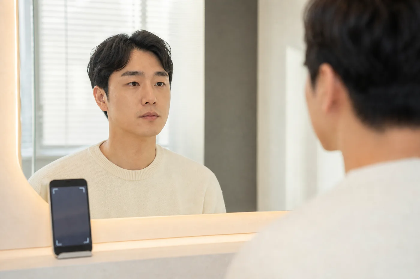 밝은 거울 앞에서 손질하지 않은 자연 눈썹을 전체 얼굴과 함께 확인하는 한국 성인 남성