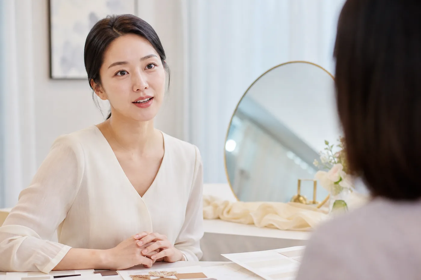 거울 앞에서 대화 거리의 얼굴과 자연스러운 눈매를 확인하는 한국 여성