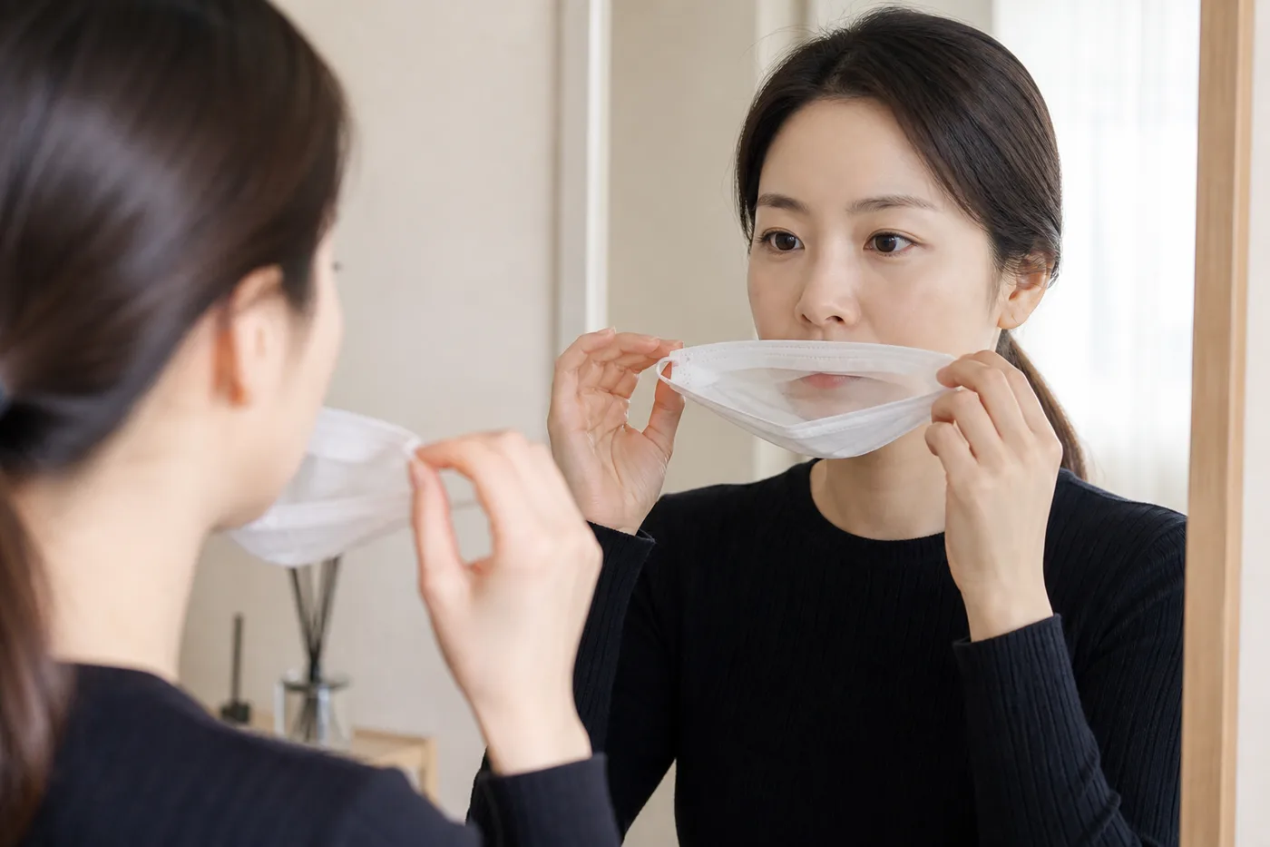 거울 앞에서 마스크 안쪽이 입술에 닿는 위치를 확인하는 한국 성인 여성