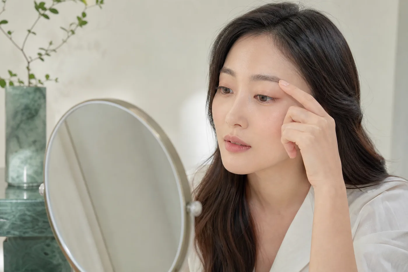 손거울로 앞머리 중앙 꼬리의 결 흐름을 살펴보는 한국 여성