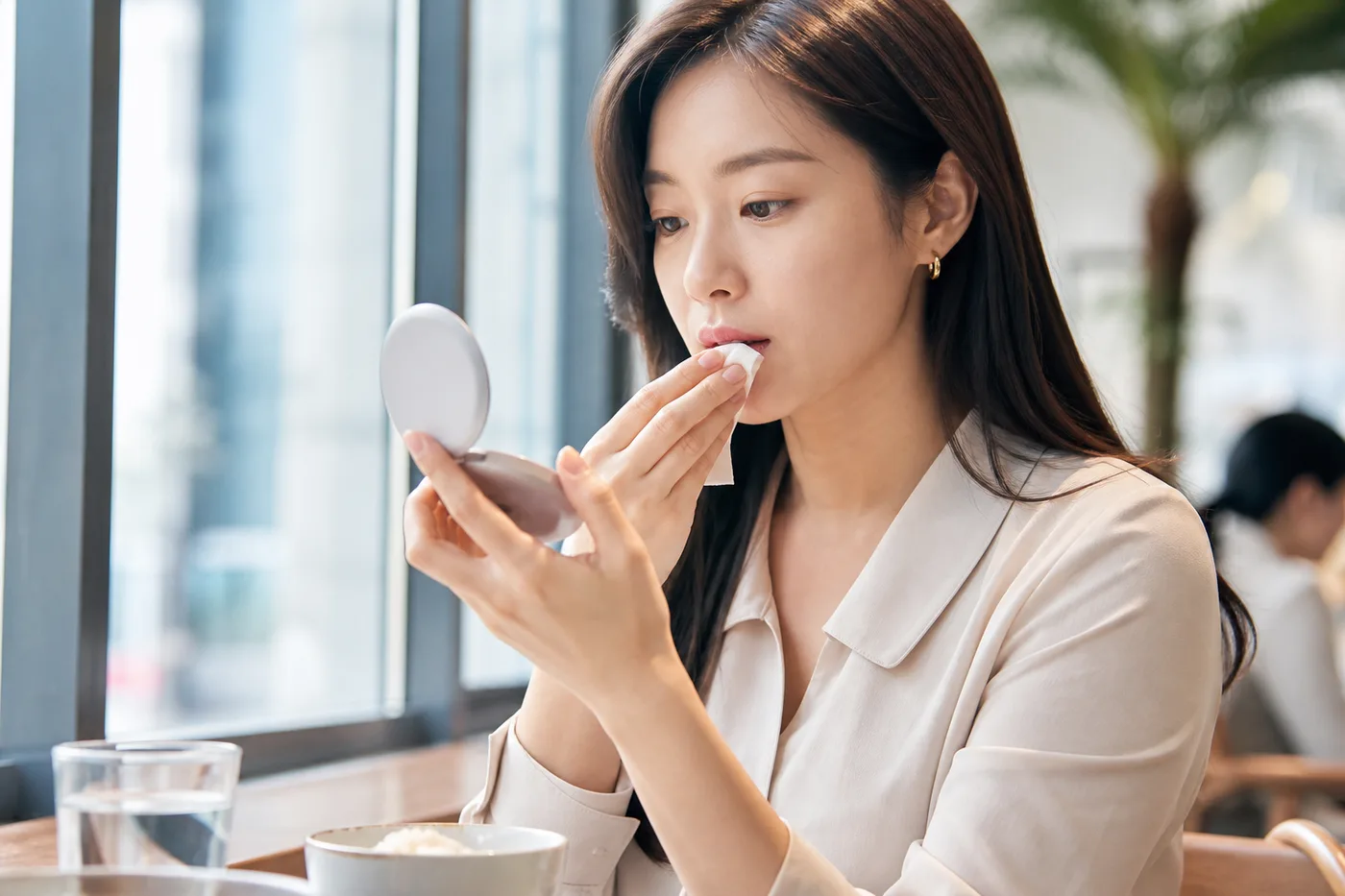 점심 식사 뒤 작은 거울로 얼굴 전체와 입술 경계를 확인하는 한국 성인 여성