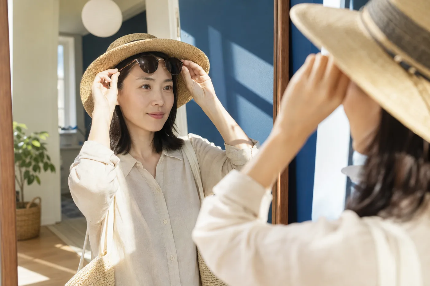 거울 앞에서 모자 챙과 선글라스의 눈썹 접촉을 확인하는 한국 여성