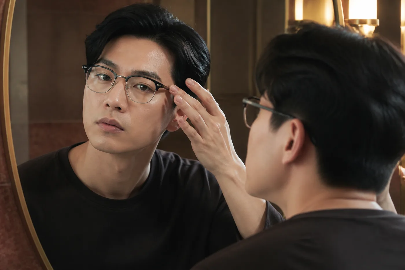안경과 헤어를 착용한 상태에서 눈썹 꼬리의 사라지는 농도를 거울로 보는 남성