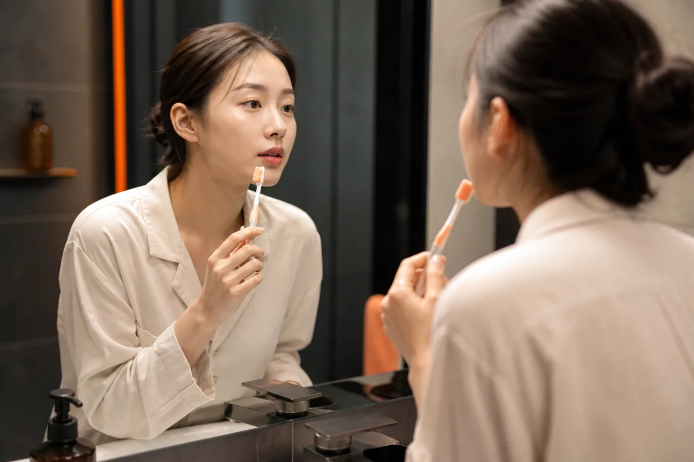 세면대 옆 칫솔을 들고 입술 접촉 경로를 메모하는 한국 성인 여성